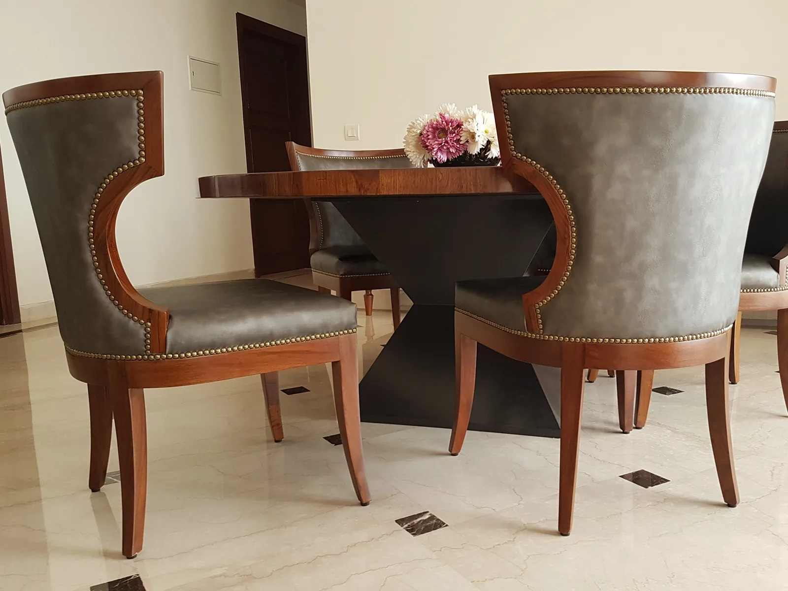 Custom grey leather dining chairs with antique brass stud detailing.