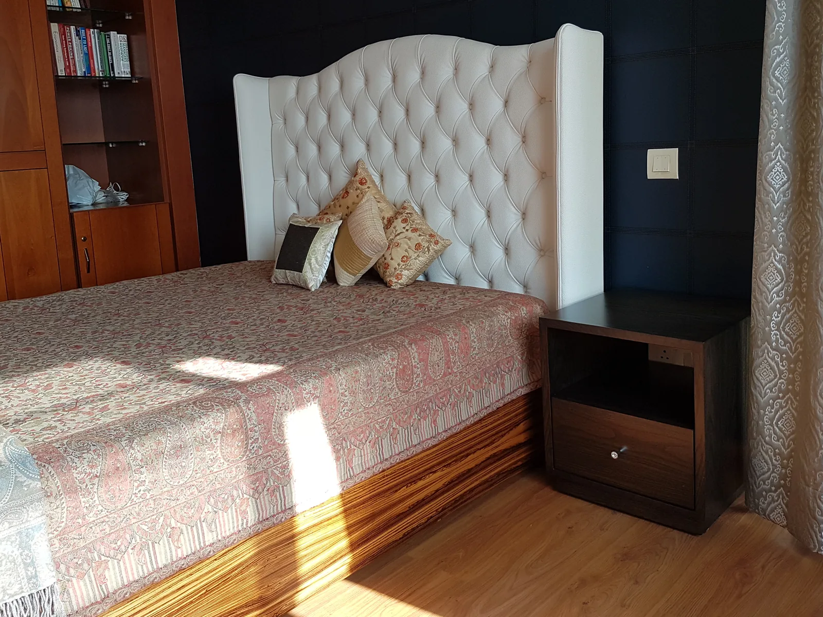 Floor-to-ceiling paneled headboard wall wrapping the bed suite.