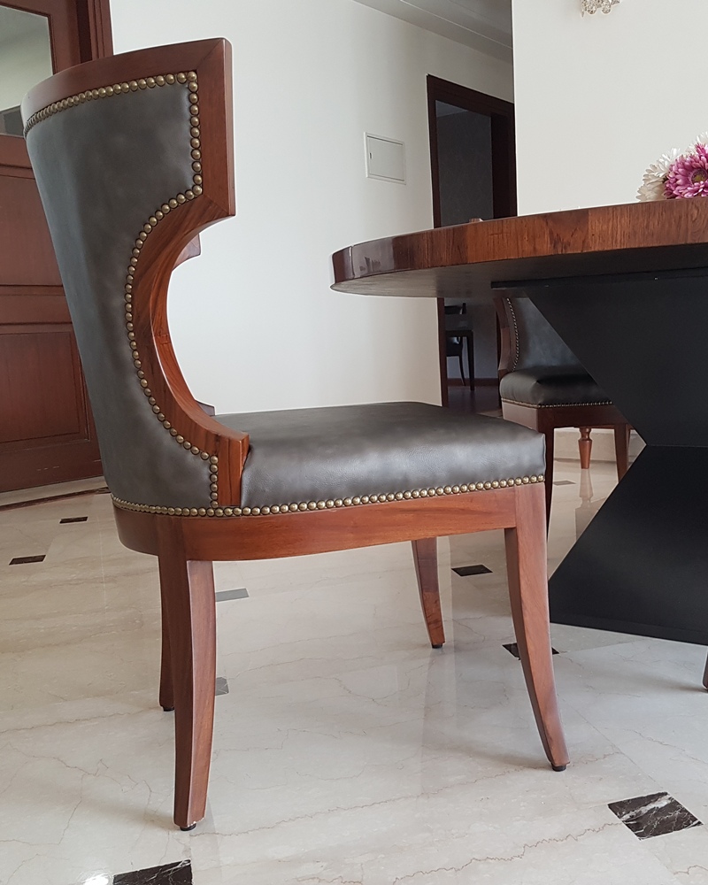 Ergonomic curved dining chair in grey leather and wood by SpaceTalk Designs, Gurgaon